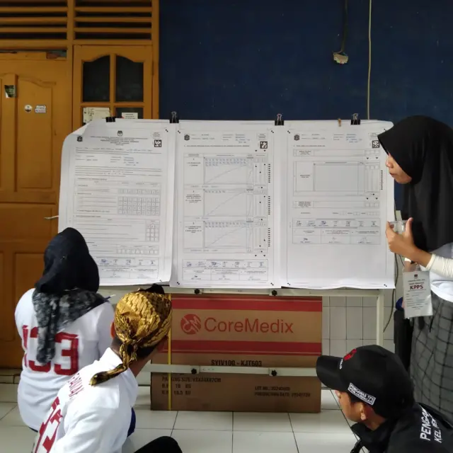 Di TPS 132, sejumlah warga tampak mengerubungi para panitia KPPS yang sedang membacakan satu per satu surat suara dari dalam kotak suara.