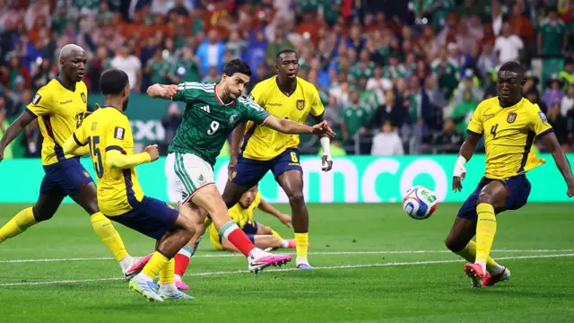 Mexico's Raul Jimenez kicks the football to score a goal while surrounded by four opposing players. 