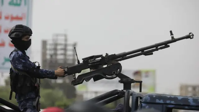 Un militar con la cara tapada empuña una ametralladora. 