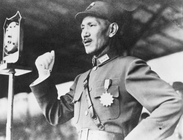 Chiang Kai-shek gesticulando com a mão em pé e falando perto de aparente microfone