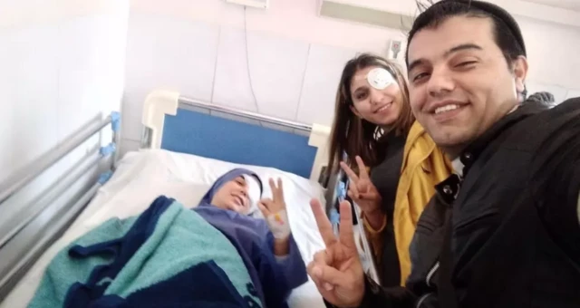 Trois personnes ayant perdu un oeil regardent l'objectif en souriant et en faisant le signe "Peace" avec deux doigts de la main.