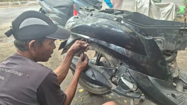 Seorang montir sepeda motor di Makassar, Kalimantan Selatan sedang membenahi kabel yang rusak.