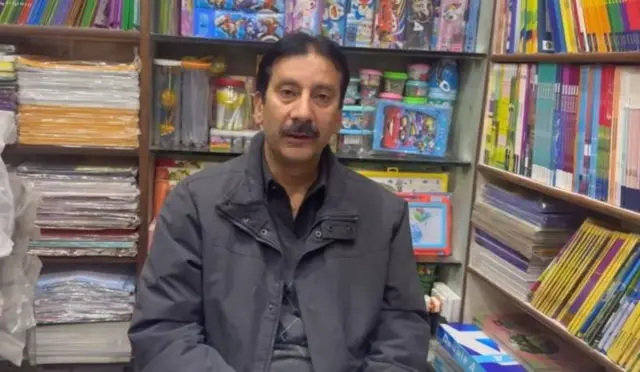 दुकान पर बैठा एक व्यक्ति 