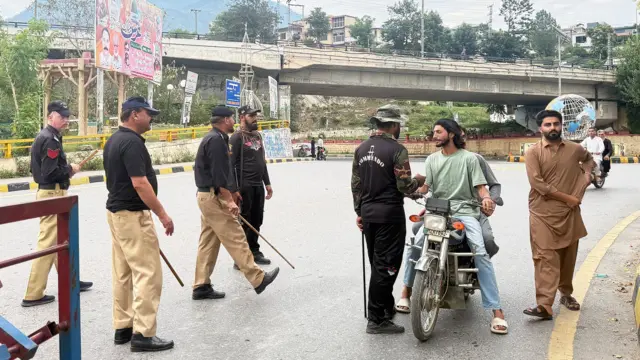 Police frisk people at a checkpoint in Muzaffarabad, the capital of Pakistan-administered Kashmir on July 15, 2026. Nine people were killed and a dozen wounded in renewed clashes between supporters of a banned protest group and security forces in Pakistan-administered Kashmir, an official said on July 15. (Photo by Sajjad QAYYUM / AFP via Getty Images)