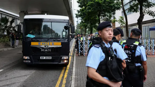 據信接載支聯會煽顛案被告人的香港懲教署囚車抵達西九龍裁判法院，多名身穿防刺背心的警員在法院停車場入口外站崗守衛（21/8/2026）