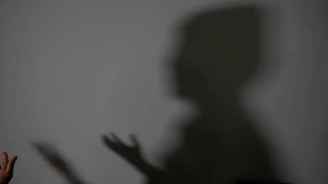 La silhouette d'Abdi (ce n'est pas son vrai nom) les mains écartées devant elle, légèrement levées vers sa poitrine.