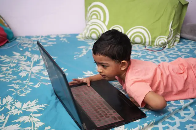 a young boy engaged in watching and exploring laptop