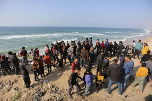 ग़ज़ा में समुद्र तट पर राहत सामग्री का इंतजार करते लोग