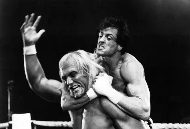 Hulk in a headlock by Sylvester Stallone, both with strained expressions, in Rocky III in 1982