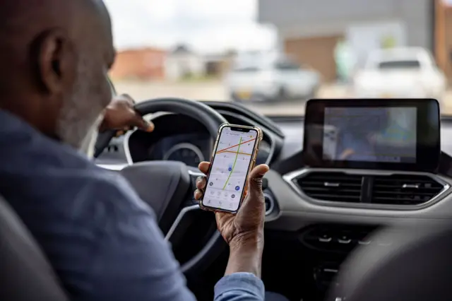 Homme âgé utilisant une application de navigation au volant de sa voiture.