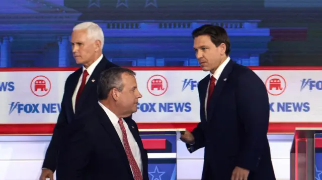 المرشحون الرئاسيون الجمهوريون (من اليسار إلى اليمين)، ونائب الرئيس الأمريكي السابق مايك بنس، وحاكم نيوجيرسي السابق كريس كريستي، وحاكم فلوريدا رون ديسانتيس يأخذون استراحة في المناظرة الأولى للموسم التمهيدي للحزب الجمهوري والتي استضافتها شبكة فوكس نيوز