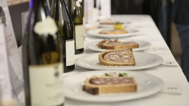 На столі стоять тарілки з порціями мʼясного рулету та пляшки з вином