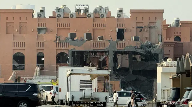 مبنى متضرر في أعقاب هجوم إسرائيلي على قادة لحماس في الدوحة مع وجود سيارة شرطة وسيارات أخرى وعدد من الأشخاص.