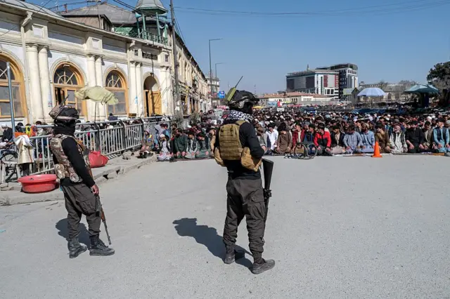 Agentes de segurança do Talebã fazem a guarda enquanto fiéis muçulmanos afegãos realizam orações na sexta-feira, durante o mês sagrado islâmico do Ramadã, em uma rua em Cabul, em 27 de fevereiro de 2026.