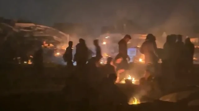 sejumlah orang menunggu konvoi bantuan dalam kegelapan