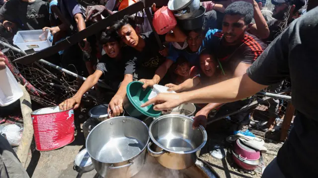 فلسطينيون يتجمعون لتلقي الطعام من مطبخ خيري، وسط أزمة جوع، في النصيرات، وسط قطاع غزة.