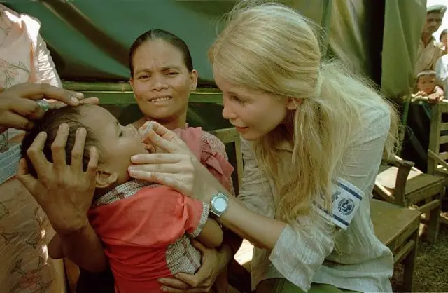 ইউনিসেভের একজন কর্মী একটি শিশুকে পোলিও টিকা খাওয়াচ্ছে