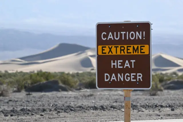 Uma placa em uma paisagem árida que diz: 'Cuidado! Perigo de calor extremo'