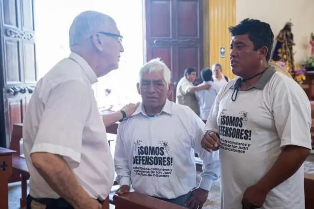 Miembros de la comunidad de Catacaos visten camisetas con el lema "somos defensores" mientras conversan con representantes de la iglesia Católica.