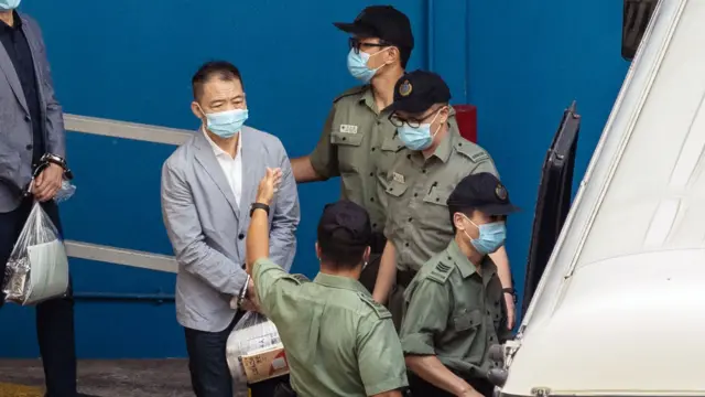 胡志偉(左,灰色外套者)被鎖上手銬,由懲教署獄警押送上囚車送往西九龍裁判法院受審(8/7/2021)
