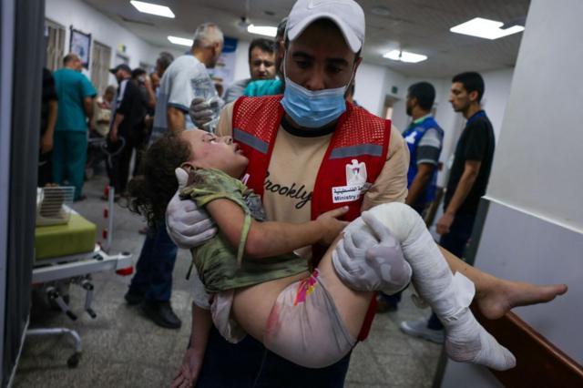 أحد رجال الإسعاف يحمل طفلاً جريحا في مستشفى بعد الغارات الجوية الإسرائيلية في رفح جنوب قطاع غزة في 13 أكتوبر 2023.