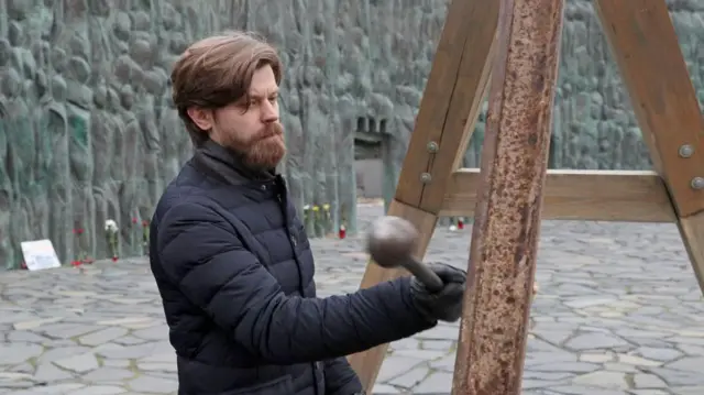 Мужчина со скорбным лицом бьет в набат