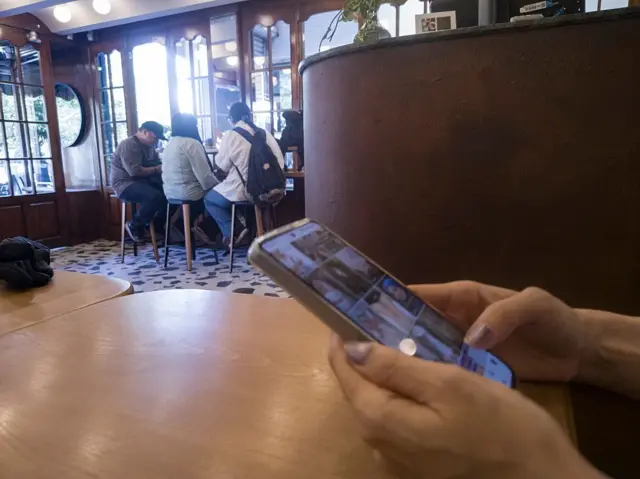 Seorang perempuan muda Iran menggunakan ponselnya di sebuah kafe di pusat kota Teheran, Iran, Selasa (26/05). Akses internet sedang dipulihkan di Iran setelah terputus selama hampir tiga bulan. 