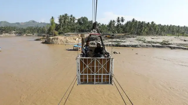 Warga menyeberangi Sungai Peusangan menggunakan kereta gantung kabel baja di Ulee Jalan, Peusangan Selatan, Bireuen, Aceh, Kamis (19/03). 