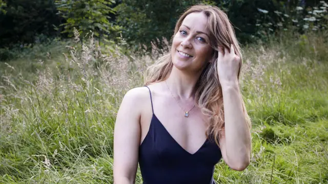 Eirian Collinge siedzi na trawie w parku.