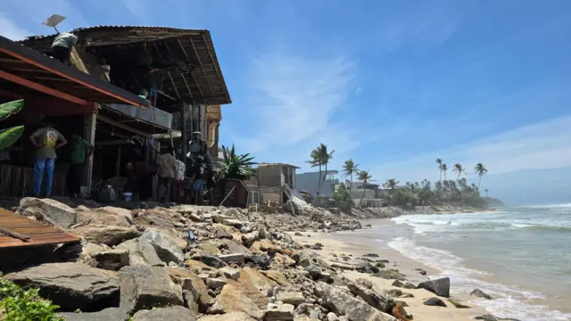 අහංගම වෙරළ තීරයේ ආරක්ෂාවට යොදා ඇති ගල් වැට අසල ඉදිකර තිබූ ආපනශාලාවක කොටසක් කඩා ඉවත් කර ඇති අයුරු