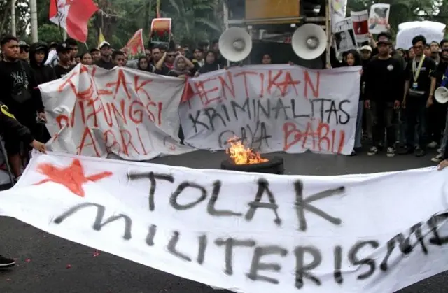 Pengunjuk rasa membakar ban saat menggelar aksi menolak UU TNI di depan Gedung DPRD Sidoarjo, Jawa Timur, Selasa (25/03).