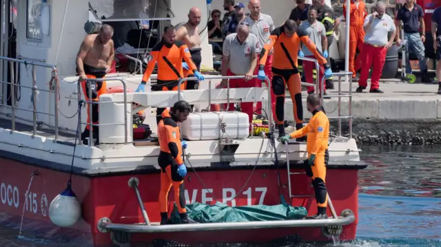 Los equipos de rescate llevan una bolsa para cadáveres a la orilla del puerto de Porticello.