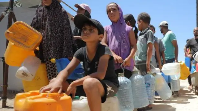 Un grupo de personas con garrafas hace cola para conseguir agua.