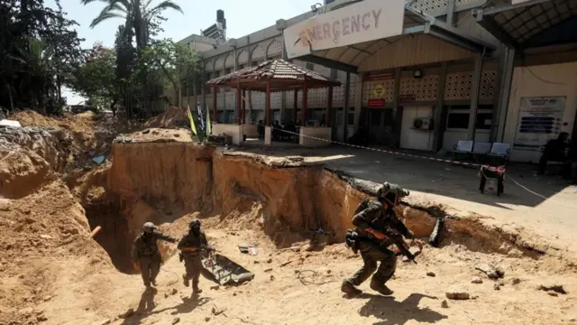 Soldados armados na saída de um túnel em frente a um hospital