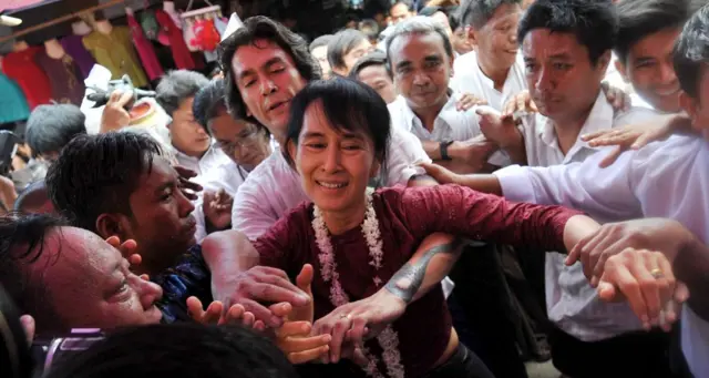 ၂၀၁၁ ခုနှစ်က ပုဂံခရီးစဥ်မှာ ဒေါ်အောင်ဆန်းစုကြည်ကို လူထုကနှုတ်ဆက်နေစဥ် သားဖြစ်သူ ကင်မ်အဲရစ်က အနားမှာစောင့်ရှောက်ပေးနေတာဖြစ်ပါတယ်။