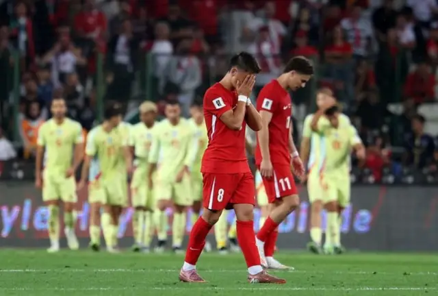 Türkiye formalı oyuncu yüzünü elleriyle kapatmış yanında üzgün bir başka oyunca geri planda İspanyalı oyuncular flu görünüyor. 