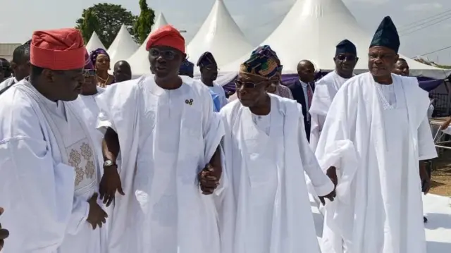 Oloye Olusegun Obasanjo wa laarin gomina ìpínlẹ̀ Eko, Babajide Sanwo-Olu àti Gómìnà ana ni ìpínlẹ̀ Ogun, Ibikunle Amosun, tí gbogbo wọ́n sì wọ aṣọ agbada àti Sokoto pẹlu fìlà funfun 