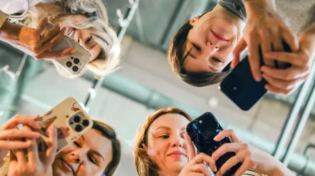 Жінки дивляться на смартфони під низьким кутом під час спілкування в сучасному приміщенні - стокова фотографія