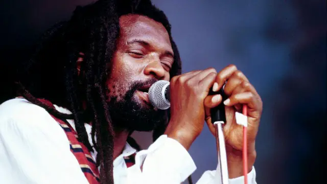Reggae Star, Lucky Dube hold microphone as e dey sing.