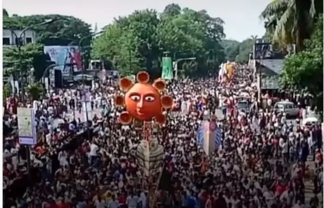 Àwọn èrò tó pọ̀ pẹ̀lú ère ńlá kan ní àárín wọn