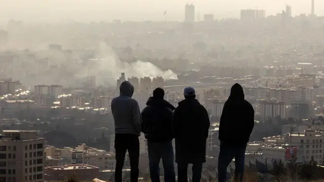 Iraníes observan Teherán desde una colina durante los ataques.