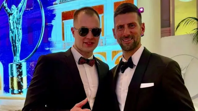 Danylo Chufarov posando ao ladounibetunibetNovak Djokovic.