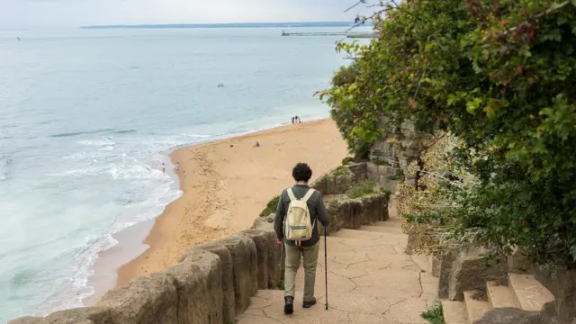 모래사장이 보이는 해안 근처에 만들어진 길 위로 한 사람이 걷고 있다