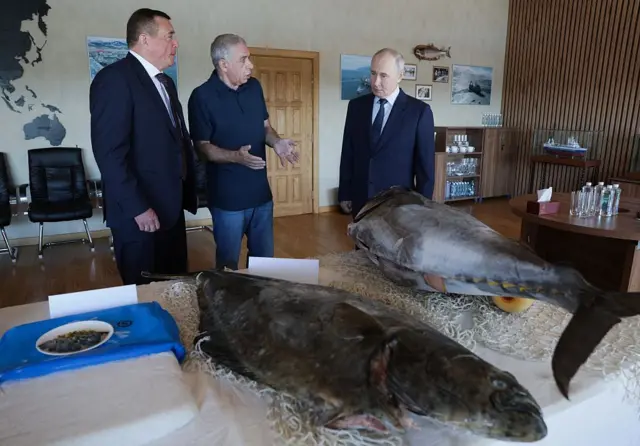 En esta fotografía de grupo distribuida por la agencia estatal rusa Sputnik, el presidente de Rusia, Vladímir Putin, visita la planta de procesamiento de pescado Yasny, en la isla de Iturup.