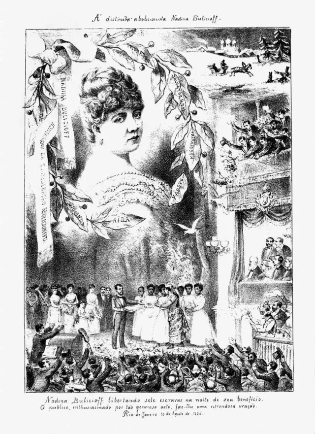 Imagem em preto e branco de pessoas no palco e várias na plateia