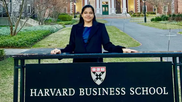 Shreya Mishra Reddy stands behind a sign with the words Harvard Business School and a crest of the institution at its campus in Boston in the United States.