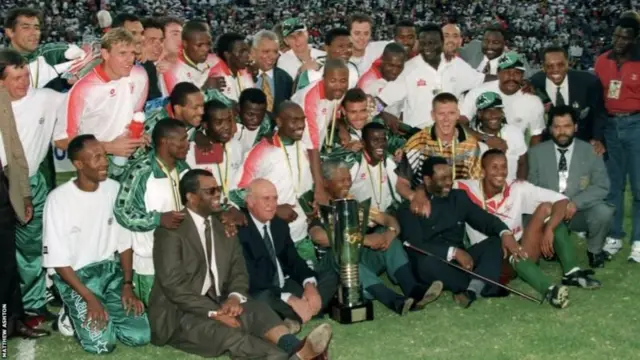 Nelson Mandela, alors président de l'Afrique du Sud, est photographié derrière le trophée, portant une réplique du maillot des Bafana Bafana, lors de la célébration de la victoire de l'Afrique du Sud en 1996.