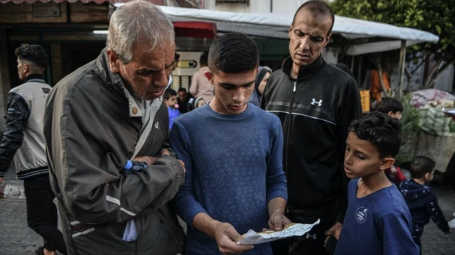 Dois homens e dois meninossporting bet apostasuma ruasporting bet apostasGaza olham para um folheto com alertasporting bet apostasevacuação emitido pelas FDI