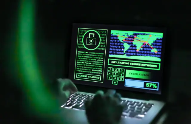 Una recreación de un ciberestafador que está frente a una computadora en un cuarto sin luz.