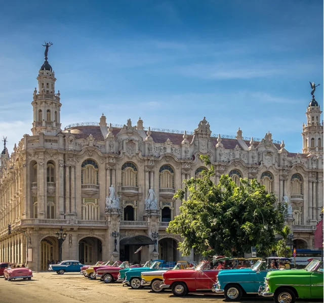 صورة لمبنى أثري ضخم به قبتان، وأمامه صف من السيارات القديمة، ذات ألوان متعددة، من أبرزها الأحمر والأصفر والأخضر.